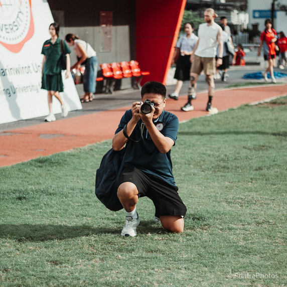 Photographer kneeling on grass, aiming a camera